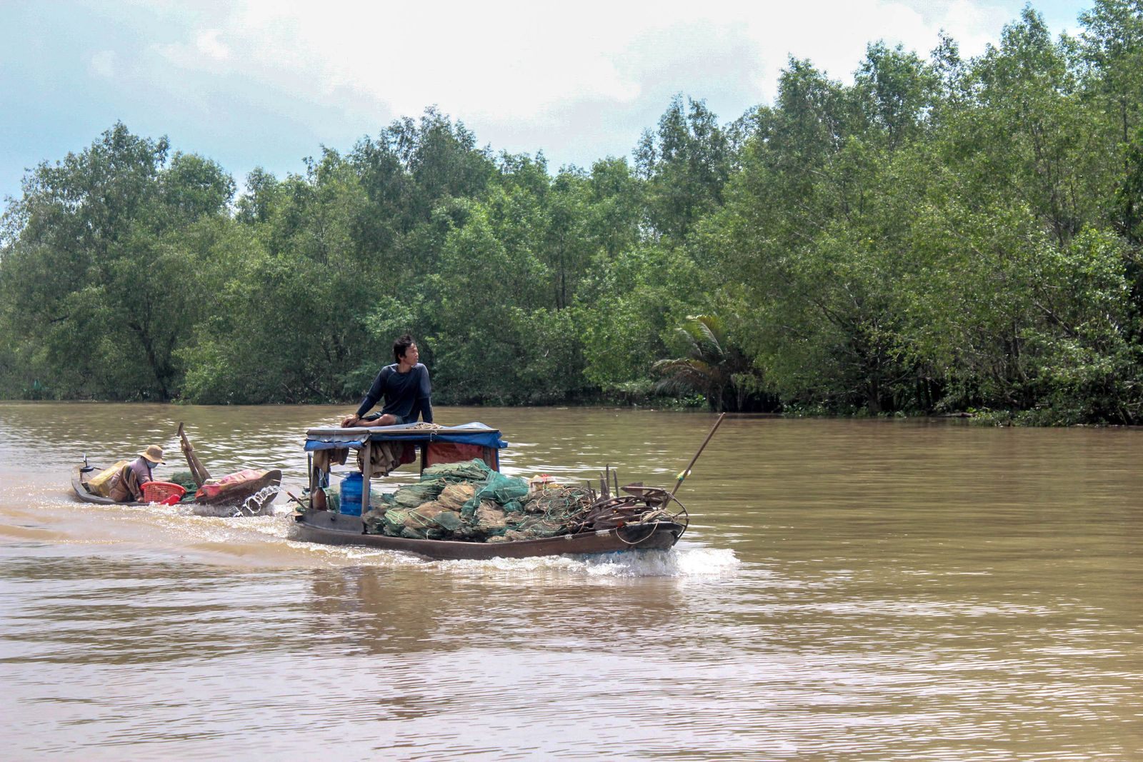 Man steering a small wooden boat on the Mekong in Vietnam